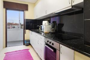una cocina con armarios en blanco y negro y una encimera púrpura. en Apartamento Vi-ana, en Viana do Castelo