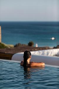 a woman in a swimming pool looking at the ocean at Mileo in Kalo Livadi