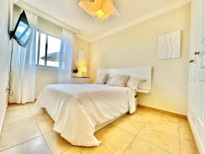 a bedroom with a white bed and a window at Apartamento Vista Faro in Poris de Abona