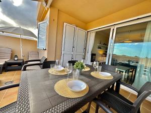 einen Esstisch mit Stühlen und einem Sonnenschirm auf dem Balkon in der Unterkunft Apartamento Vista Faro in Poris de Abona