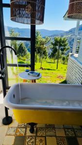 bañera frente a una ventana con vistas en Cabana Alpha - Pousada Colina dos Ventos, en Urubici