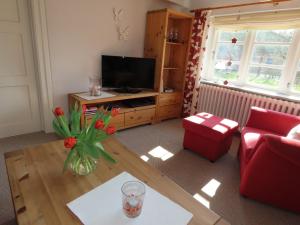 a living room with a television and a vase of flowers at Ferienhaus Zur Alten Post 1 in Ockholm