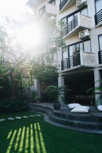 a building with the sun shining on the grass at Surf Motel in Canggu