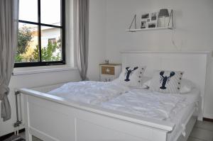 een wit bed in een witte slaapkamer met een raam bij Buitenplaats 90 in Callantsoog