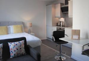 a bedroom with a bed and a table and a kitchen at Cotels at The HUB Serviced Apartments, Superfast Broadband, Central Location, Free Parking in Milton Keynes