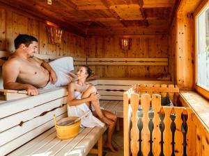 um homem e uma mulher sentados numa sauna em Holiday Home Hirtabua by Interhome em Pichl