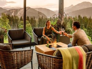 un homme et une femme assis autour d'une table avec des verres à vin dans l'établissement Holiday Home Premium Waldjuwel by Interhome, à Pichl