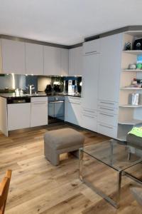 a large kitchen with white cabinets and a glass table at Apartment Haus Sunneschy Whg- 301 by Interhome in Parpan