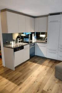 帕潘的住宿－Apartment Haus Sunneschy Whg- 301 by Interhome，厨房铺有木地板,配有白色橱柜。