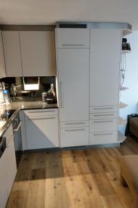 帕潘的住宿－Apartment Haus Sunneschy Whg- 301 by Interhome，厨房铺有木地板,配有白色橱柜。