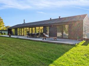 une maison avec une grande terrasse et une pelouse dans l'établissement Holiday Home Tessa - 1-6km from the sea in Sealand by Interhome, à Græsted
