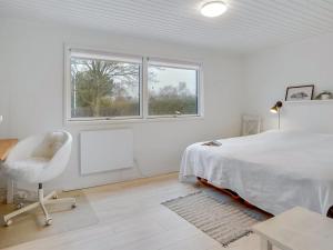 a bedroom with a bed and a chair and a window at Holiday Home Elma - 350m from the sea in SE Jutland by Interhome in Juelsminde