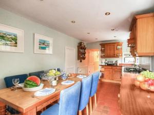 une cuisine avec une table en bois et des chaises bleues dans l'établissement The Townhouse At Green Edge, à Beaumaris
