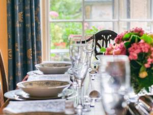 une table avec des assiettes, des verres et un vase de fleurs dans l'établissement The Townhouse At Green Edge, à Beaumaris