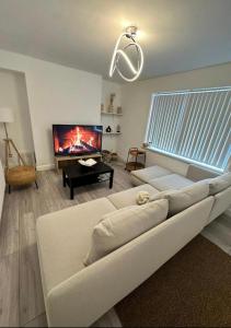 a living room with a white couch and a tv at The Maison- Cozy home stay in Nottingham