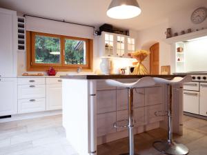 una cucina con armadi bianchi e un'isola con sgabelli di Chalet Chalet Le Haut Pré by Interhome a Villars-sur-Ollon