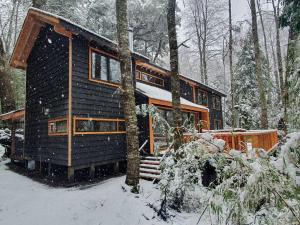 una cabaña de madera en el bosque en la nieve en Espectacular y Amplia Casa en Reserva Huilo Huilo, en Reserva Biológica Huilo Huilo
