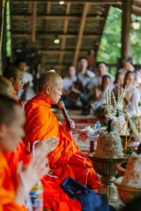 un hombre sentado con un micrófono delante de una multitud en Maison Barn Laos en Luang Prabang