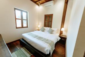 a bedroom with a large white bed with a window at Maison Barn Laos in Luang Prabang