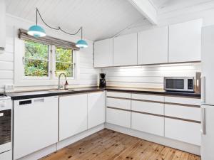 a kitchen with white cabinets and a window at Holiday Home Eddi - 10km from the sea in Djursland and Mols by Interhome in Rønde