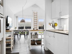 una cucina con armadi bianchi e tavolo con sedie di Apartment Helemine - 400m from the sea in NW Jutland by Interhome a Fjerritslev