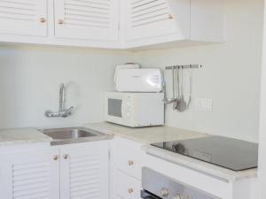 a kitchen with white cabinets and a sink and a microwave at Apartment Son Bou Gardens PLUS by Interhome in Son Bou +28 photos
