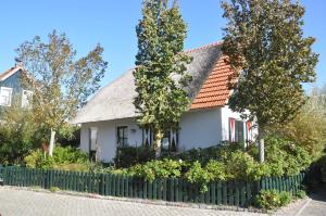 una casa blanca con árboles y una valla en Buitenplaats 90, en Callantsoog