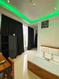 a bedroom with a bed with a green lighting at The Marc Vannelli Oslob in Oslob