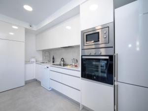 eine Küche mit weißen Schränken und einem Edelstahlofen in der Unterkunft Apartment Isea Calpe-6 by Interhome in Calpe