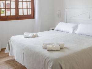 two towels are sitting on a white bed at Apartment Son Bou Gardens Apt 3 dorm by Interhome in Son Bou