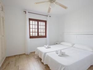 two beds in a white room with a ceiling fan at Apartment Son Bou Gardens Apt 3 dorm by Interhome in Son Bou +23 photos