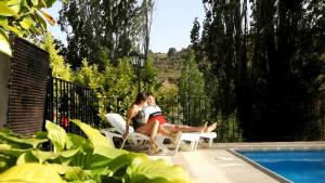 una mujer sentada en una silla junto a una piscina en Casa rural El Salero Piscina campo de fútbol y voley chimenea barbacoa en Moratalla