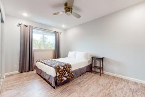 a white bedroom with a bed and a window at Orchid Land in Keaau