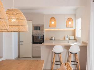 a kitchen with white cabinets and bar stools at Holiday Home Son Bou Sunset 49 by Interhome in Alaior