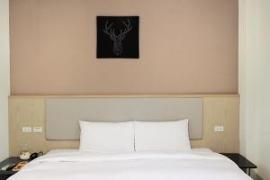 嘉義市的住宿－偶然行旅，一张铺有白色床单的床和墙上的鹿的照片