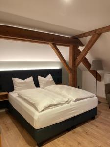 un grande letto in una camera con travi in legno di Hotel Gasthof Stieglers 