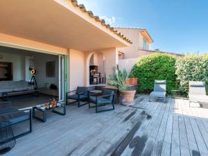 Un patio con sillas y mesas en una terraza de madera. en Holiday Home Verde by Interhome, en Porto Vecchio