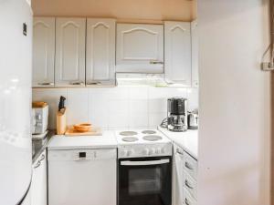 La cuisine est équipée de placards blancs et d'un four avec plaques de cuisson. dans l'établissement Holiday Home Erätuli 1 by Interhome, à Hyrynsalmi