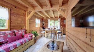 Sala de estar de una cabaña de madera con sofá y mesa en Chalet MB, en Saint-Jean-dʼAulps