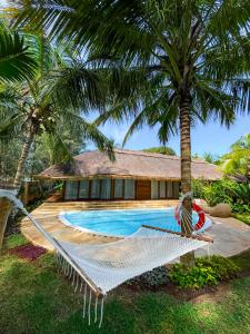 a hammock in front of a house with a swimming pool at Tulia Zanzibar Unique Beach Resort in Pongwe