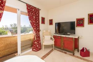 a bedroom with a tv and a bed and a window at Spikes in Guadiaro