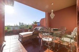 eine Terrasse mit einem Sofa, einem Tisch und Stühlen in der Unterkunft Spikes in Guadiaro