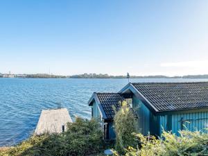 Holiday Home Sjuhalla utsikten - B في Nättrabyhamn: مبنى ازرق على شاطئ البحيرة