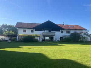 une grande maison blanche avec une grande pelouse verte dans l'établissement Ferienhaus zur schönen Aussicht, à Teisendorf