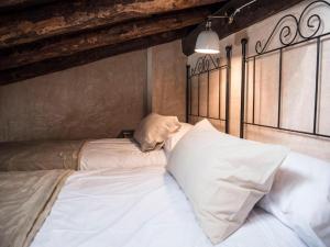 uma cama com lençóis brancos e almofadas num quarto em AbenRazin Turístico Noguera em Albarracín