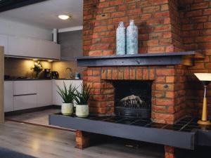 d'un salon avec une cheminée en briques et une cuisine. dans l'établissement Apartment Delfzijl by Interhome, à Delfzijl