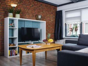 a living room with a table and a television at Apartment Delfzijl by Interhome in Delfzijl