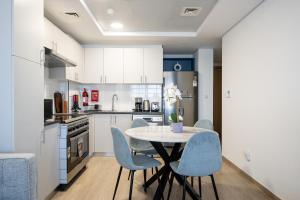 a kitchen with a table and blue chairs at ALH Vacay - The Nook 1 - 2 Bedrooms - Near Metro in Dubai