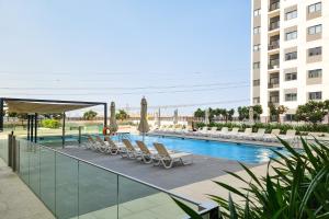 a swimming pool with chairs and umbrellas next to a building at ALH Vacay - The Nook 1 - 2 Bedrooms - Near Metro in Dubai