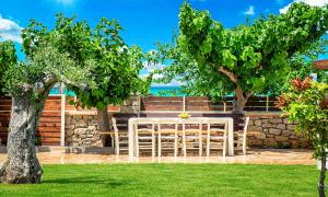 a table and chairs in a yard with trees at Cretan Sunrise Villa Heated Pool in Dhimitroulianá